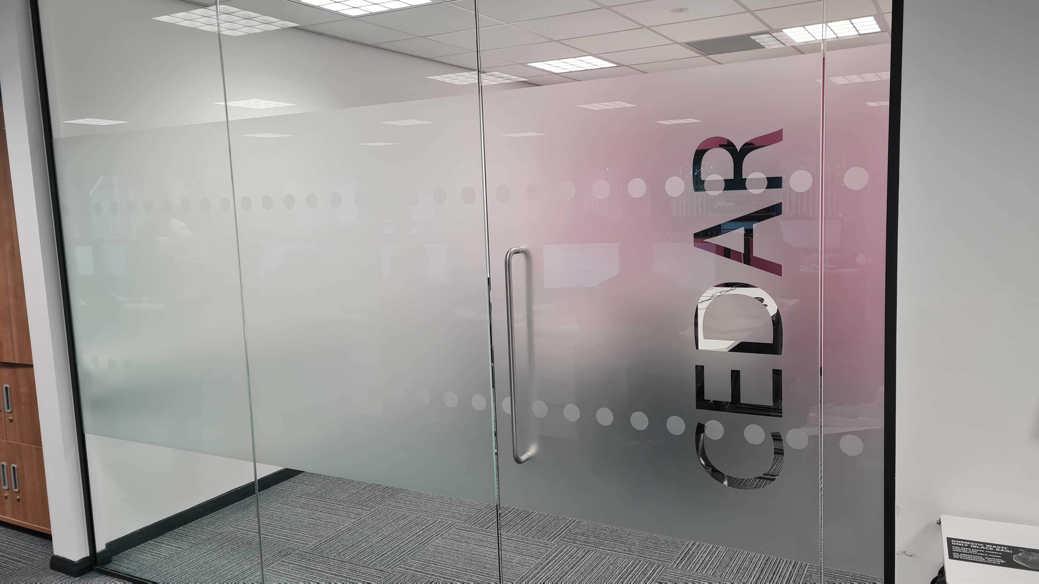 Cedar branded office glass partition with DDA compliance dots and pink gradient logo manifestation, Bristol, by Deco Studio